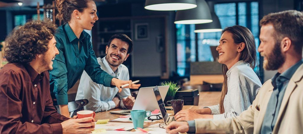 Marketingteam diskutiert gemeinsam am Schreibtisch über aktuelle Projekte - Symbolbild Teamwork und Leadership