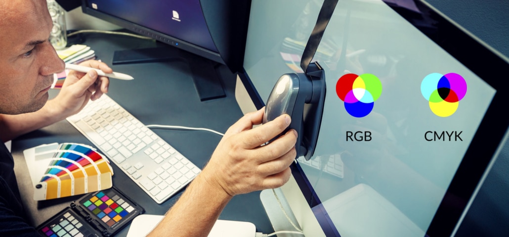 Grafiker kalibriert Computermonitor mit Spektralphotometer - Symbolbild RGB und CMYK