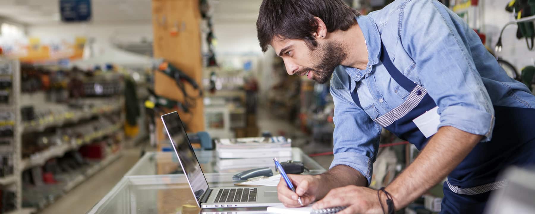 Employee looks at the laptop for new products - Symbolic image for retailer portal / product portal